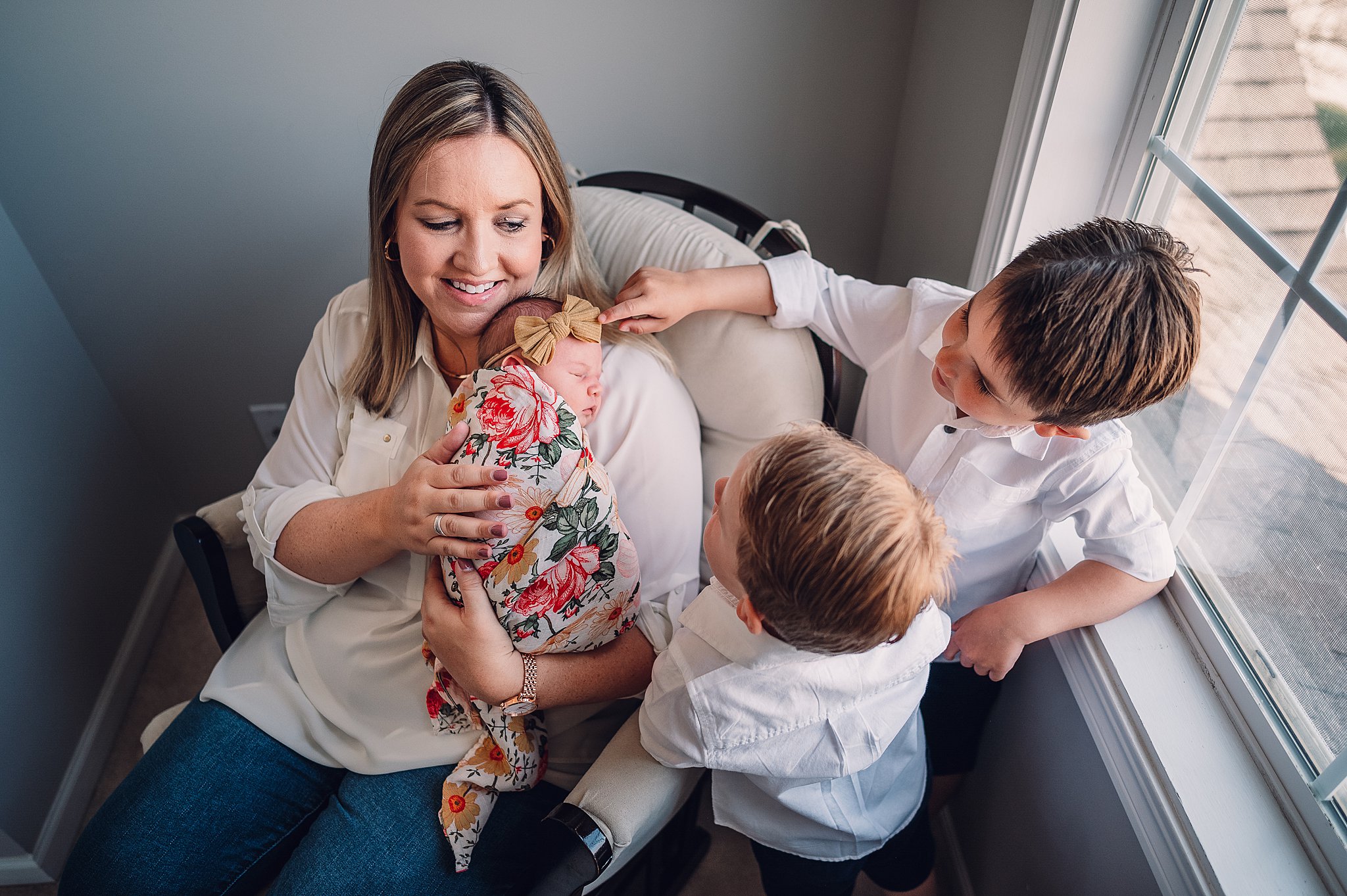 Lifestyle newborn portrait with mom and big brothers in the nursery