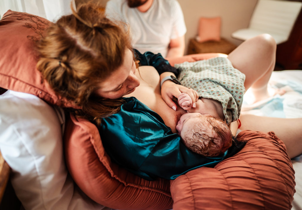 mother nursing newborn after home birth, Mackenzie Thada Photography