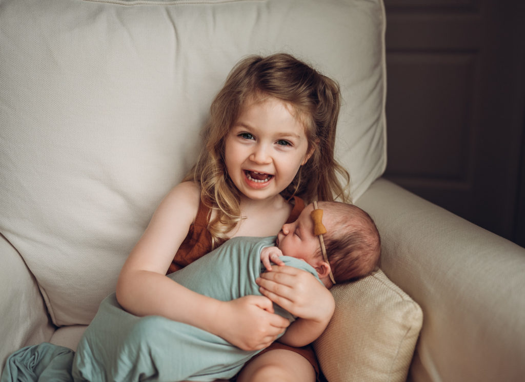 Big sister holding newborn baby